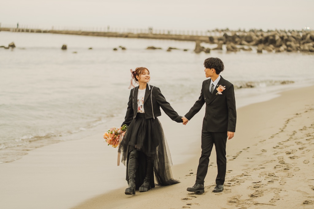 黒い衣装で海岸を歩くカップル