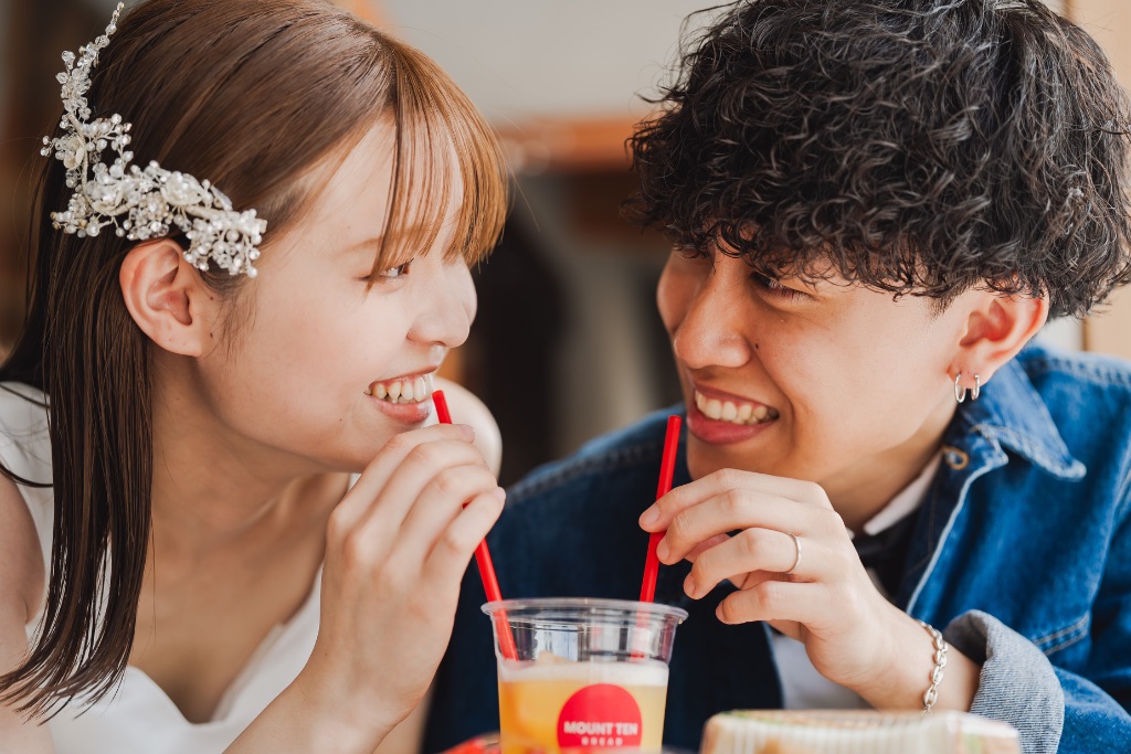 カフェでストローで飲み物を飲み見つめ合うカップル