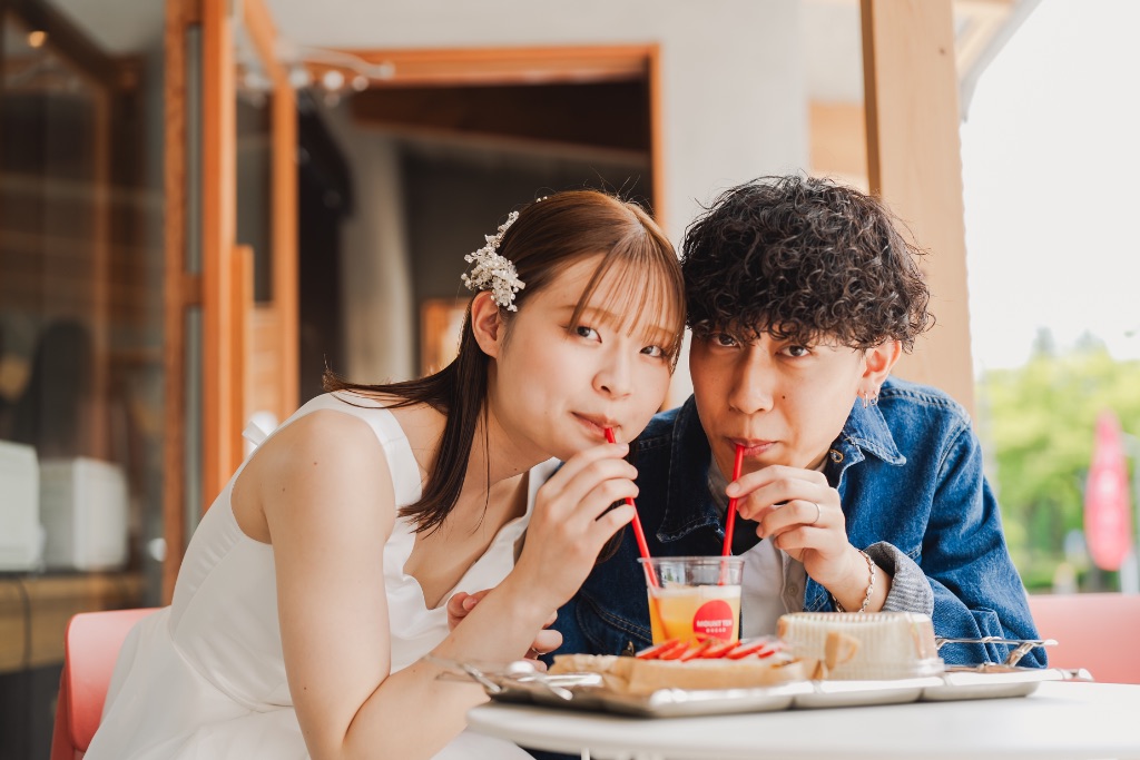 カフェのテラスでストローで飲むカップル