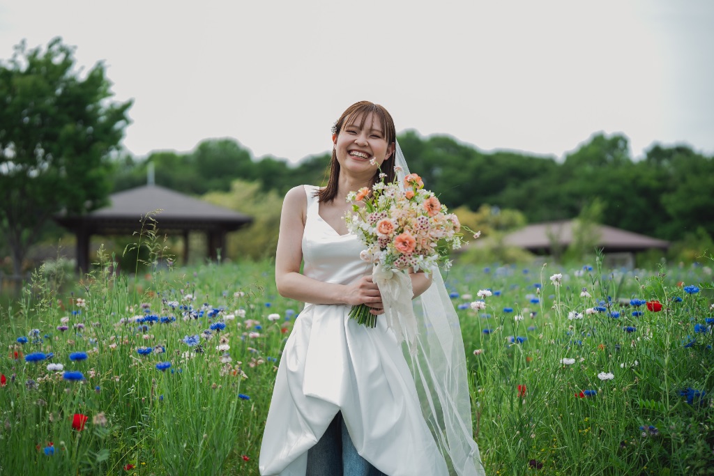 カラフルな花畑の中で笑う花嫁