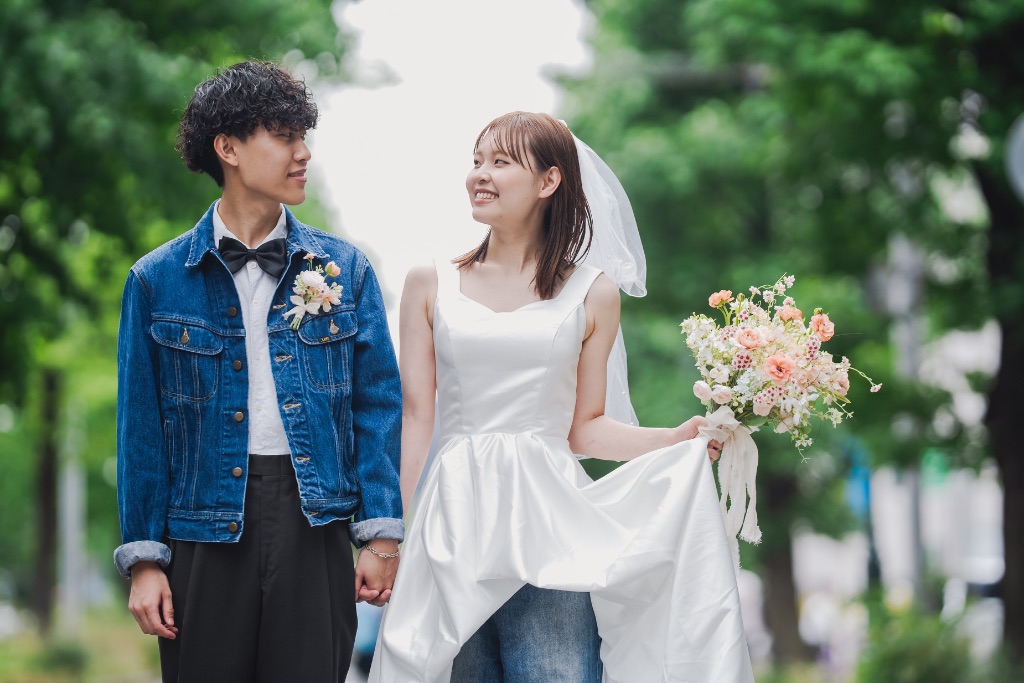 緑の並木道を手をつないで歩くカップル