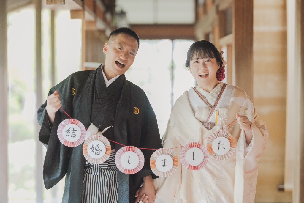 着物で「結婚しました」ボードを持って笑うカップル