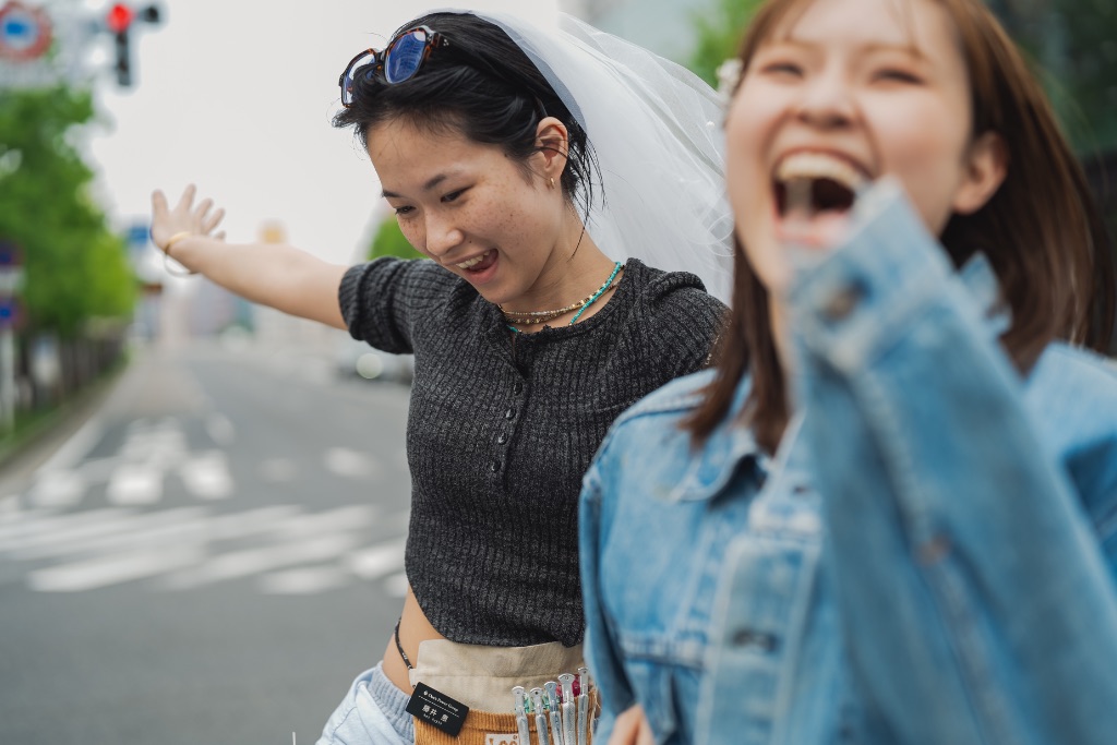 ベールをつけた女性と友人が街で笑う