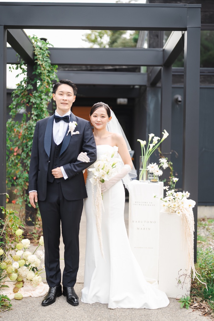屋外でウェルカムボードの前に並ぶ新郎新婦の婚礼撮影作例